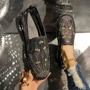Close-up of black loafers decorated with colorful rhinestones and heart patterns.