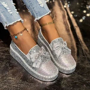 Close-up view of silver glitter loafers featuring rhinestone toes and elegant ribbon bows