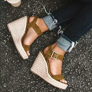 Primo piano di espadrillas con zeppa in camoscio verde oliva e suola in iuta.