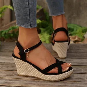 Side view of stylish black cross-strap wedge sandals with a natural braided platform