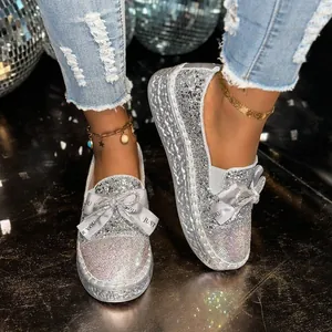 Close-up of women's silver glitter loafers with rhinestone bow and platform sole