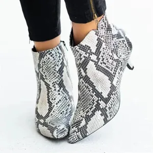 Gros plan de bottines élégantes à motif serpent avec bout pointu et talons aiguilles.
