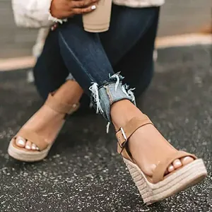 Dettaglio di eleganti sandali con zeppa in corda color cuoio indossati da modella