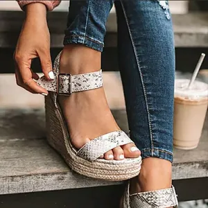 Primo piano di sandali espadrillas con zeppa stampa serpente per donna con fibbia alla caviglia