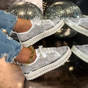 Close-up detail of white platform sneakers covered in sparkling silver rhinestones and glitter