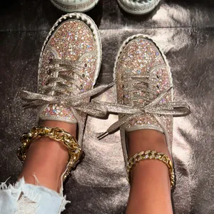 Nahaufnahme von champagnerfarbenen Glitzer-Sneakers mit funkelnden Metallic-Schnürsenkeln