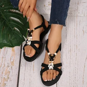 Close-up of Bohemian black flat sandals with decorative beads and butterfly accent