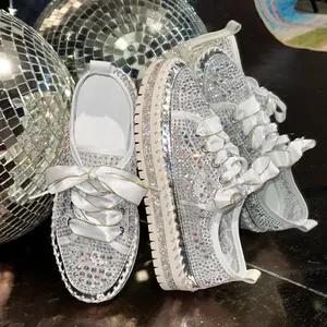 Detail of white platform sneakers with sparkling rhinestones and satin ribbon laces