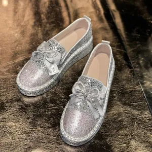 Close-up view of sparkling silver rhinestone loafers with elegant ribbon bow detail