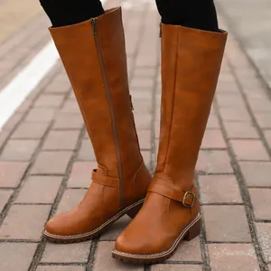 Close-up detail of stylish tan knee-high rider boots featuring side zipper and buckle strap