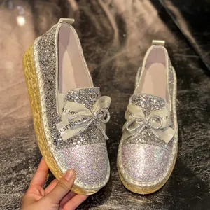 Detailed view of sparkling rhinestones and ribbon bow on women's slip-on loafers.