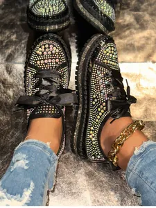 Close-up of black platform loafers with colorful rhinestones and silk laces