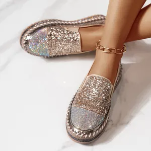 Dettaglio di mocassini con zeppa glitterati e strass indossati con cavigliera