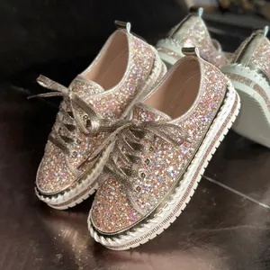 Nahaufnahme goldene Plateau-Sneaker für Damen mit Glitzer-Finish und Strass-Sohle