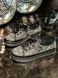 Macro view of black platform sneakers covered in iridescent sparkling rhinestones.