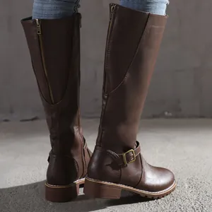 Close-up of brown knee-high riding boots with functional back zipper and buckle strap