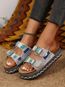 Close-up detail of women's wedge platform slippers with blue rhinestones and buckles