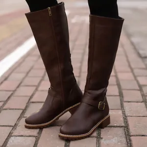 Outdoor street view of dark brown flat knee-high rider boots with buckle details