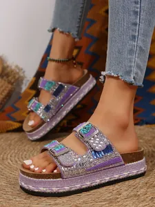 Close-up of purple platform sandals with sparkling rhinestones and double buckles.