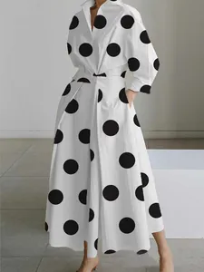 Close-up of a white shirt dress featuring bold black polka dots and lapel collar