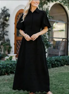 Détail d'une robe noire élégante à col POLO avec broderie anglaise délicate.