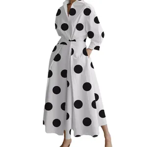 Elegant white long-sleeved polo collar dress with large black polka dots and flared skirt.