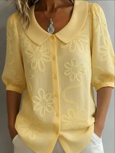 Detail of yellow retro blouse featuring floral embroidery and a Peter Pan collar.