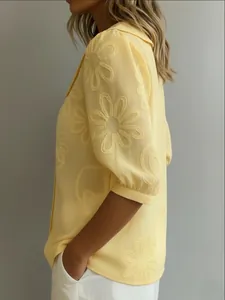 Detail view showing the textured yellow floral embroidery on a casual shirt sleeve