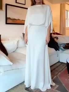 Detailansicht eines eleganten weißen Satinkleides mit drapierten Ärmeln und fließendem Rock.