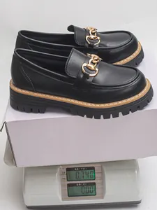 Macro view of black chunky platform loafers with gold chain weighing 0.74 kg