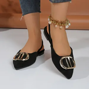Close-up detail of black pointed-toe flat slingback sandals with large gold metal buckle