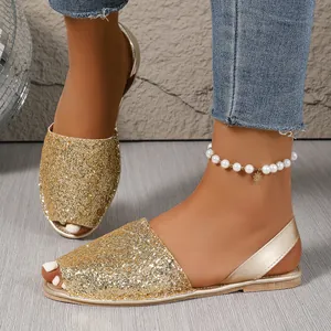 Detailed shot of shiny gold glitter peep-toe flat sandals with slingback straps