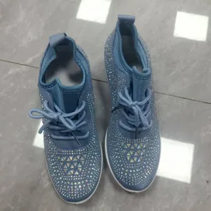 Détail de baskets en maille bleu clair ornées de strass scintillants et lacets.