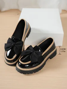 Close-up view of black patent leather bow loafers featuring a 4.5cm thick platform sole
