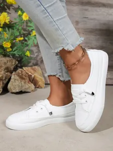 Side view of women's white casual board shoes with lace-up detail and frayed denim jeans