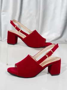 Detail shot of red velvet chunky heel sandals with elegant gold-tone metal buckles.