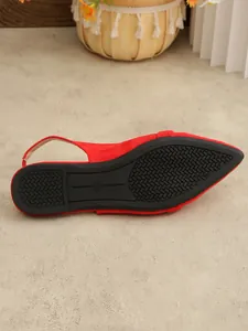 High-quality detailed view of the black non-slip sole on red suede slingback flat sandals