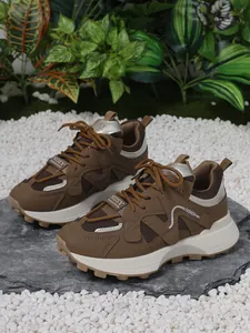 Profil détaillé de baskets tendance marron à semelles épaisses sur pierre naturelle.