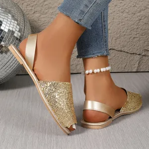 Close-up of sparkly gold glitter flat sandals with peep-toe and soft sole