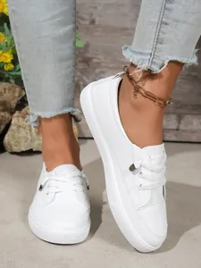 Close-up view of women's white platform sneakers featuring metallic lace-up details