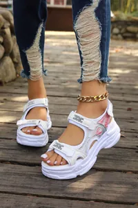 Detailed shot of white platform sporty sandals with velcro straps and pink accents