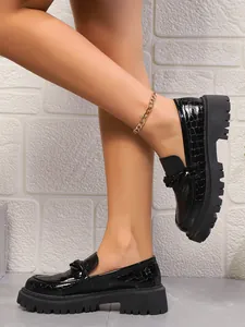 Vue détaillée de mocassins noirs à motif crocodile avec une semelle épaisse
