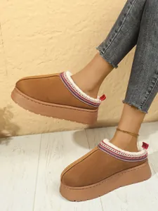 Detalle de pantuflas con plataforma marrones con forro de pelo sintético y bordado