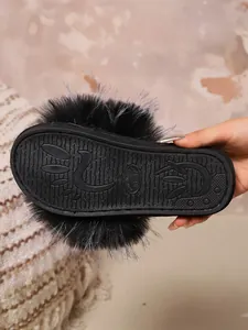Detailed view of the durable anti-slip sole on a black fuzzy plush slipper for women