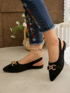 Detail view of black suede slingback flats with gold horsebit chain on pointed toe.