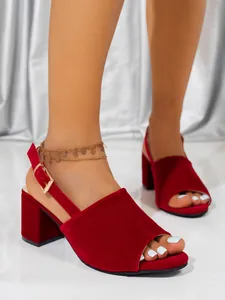 Macro view of the plush red velvet texture and gold buckle on a stylish block heel sandal