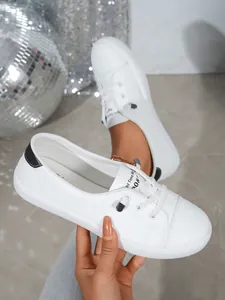 Close-up detail of stylish women's white low-top sneakers with a sleek round toe.