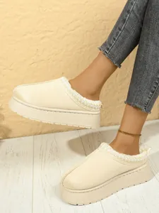 Detalle de los zuecos beige con plataforma forrados de pelo y ribete bordado