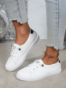 Close-up of white casual women's sneakers with black heel accent and round toe.