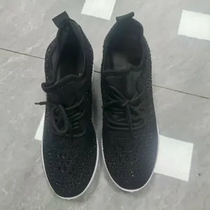 Gros plan sur des baskets noires avec des détails en strass et des lacets noirs classiques